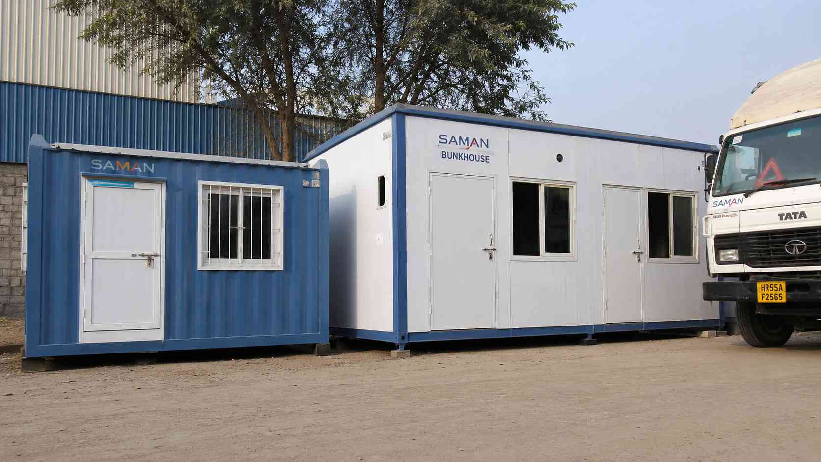 A steel blue porta cabin house beside a larger bunkhouse unit in SAMAN's prefab house range.