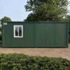 Forest green porta cabin house seen from the side, showing its full length and side window.