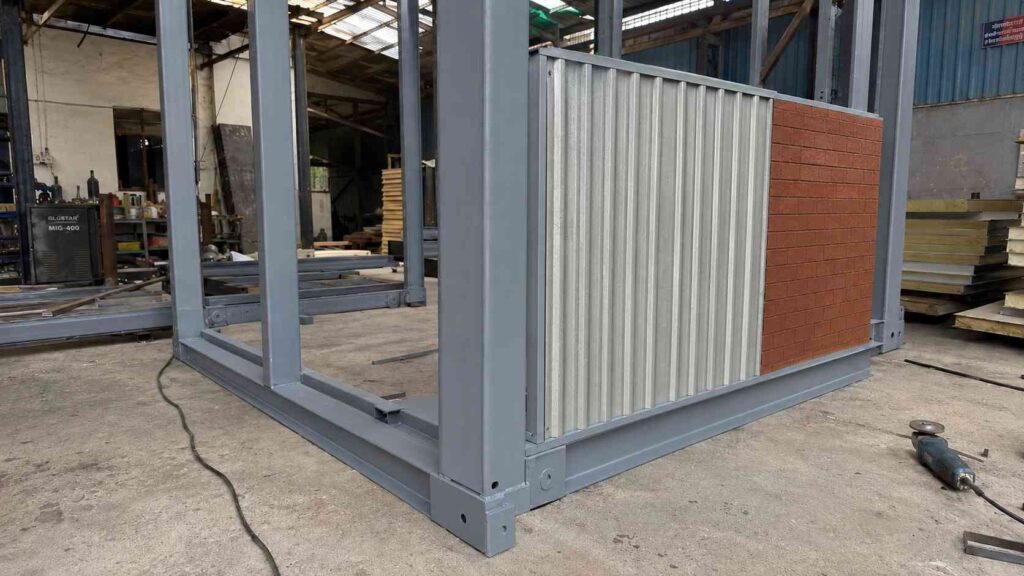  Close-up of porta cabin MS frame and PUF sandwich panel construction with brick terracotta accent panel