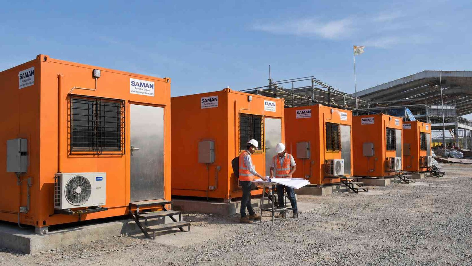 Engineers review drawings outside a Safety Orange portable container offices fleet commissioned at a Gujarat industrial facility.