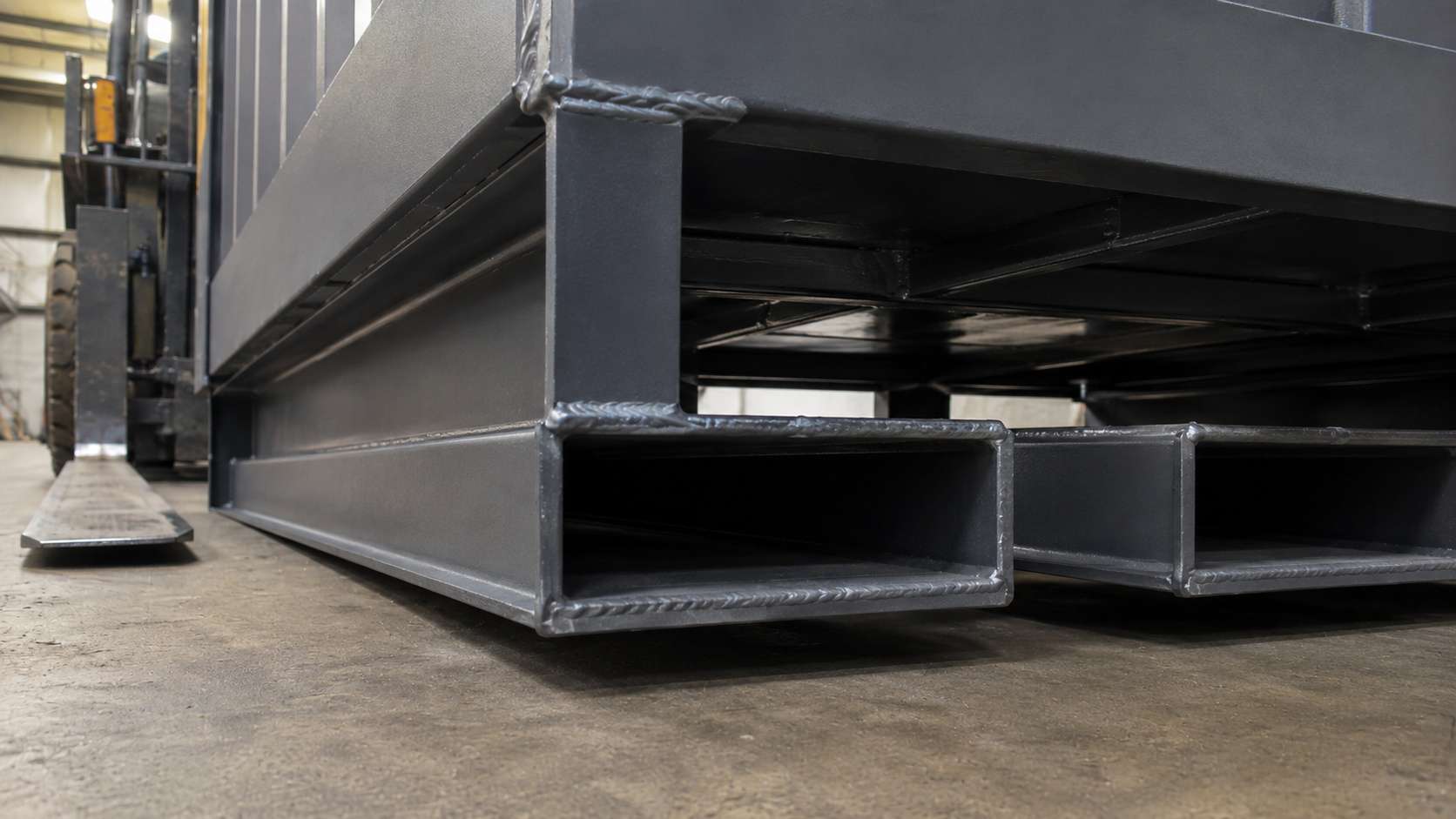 Forklift channel in the steel skid base of a portable security cabin, with forklift tine in background.