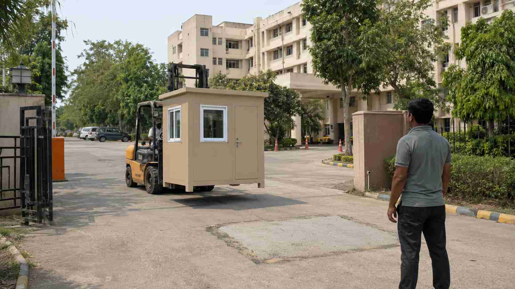 Sandstone beige portable security cabin lowered into position at a hospital or society gate during relocation.