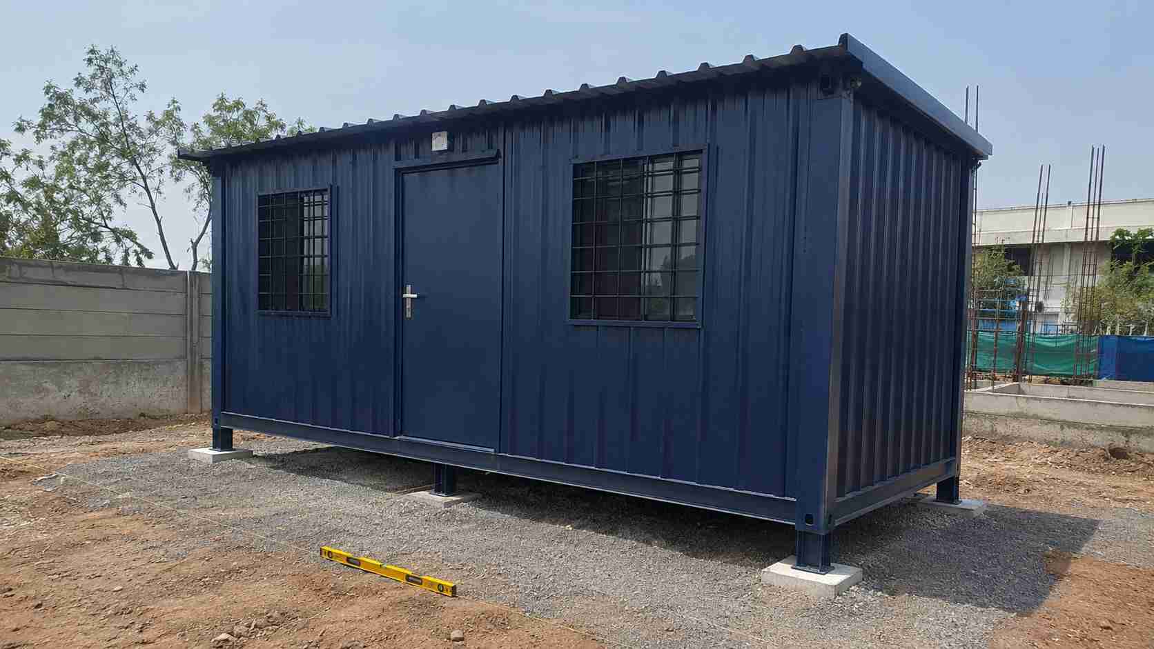 Navy portable shed set on a levelled gravel pad with concrete footing pads under the frame
