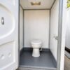 Interior of a portable toilet cabin showing toilet pan, water inlet tap and anti-skid floor