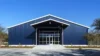 Dark navy pre-engineered building front elevation with glass entrance doors and white eave trim under a clear sky.