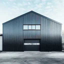Anthracite grey pre-engineered building structure with gable steel frame, clerestory windows and roller shutter entry.