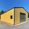 Yellow pre-engineered building structure with blue trim and roller shutter on a prepared gravel base.