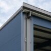 Corner detail of a steel-blue pre-engineered building showing steel frame, PUF panel and roof trim