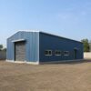 Steel-blue pre-engineered building supplied and erected on a cleared industrial plot, single-storey