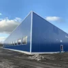 Long blue and white pre-engineered steel building with ribbon windows seen along its clear-span length.