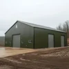 Olive-green pre-engineered steel building with roller shutters on a freshly graded gravel site.