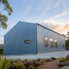 Steel-grey pre-engineering structure with a single-slope roof and lit windows at dusk.