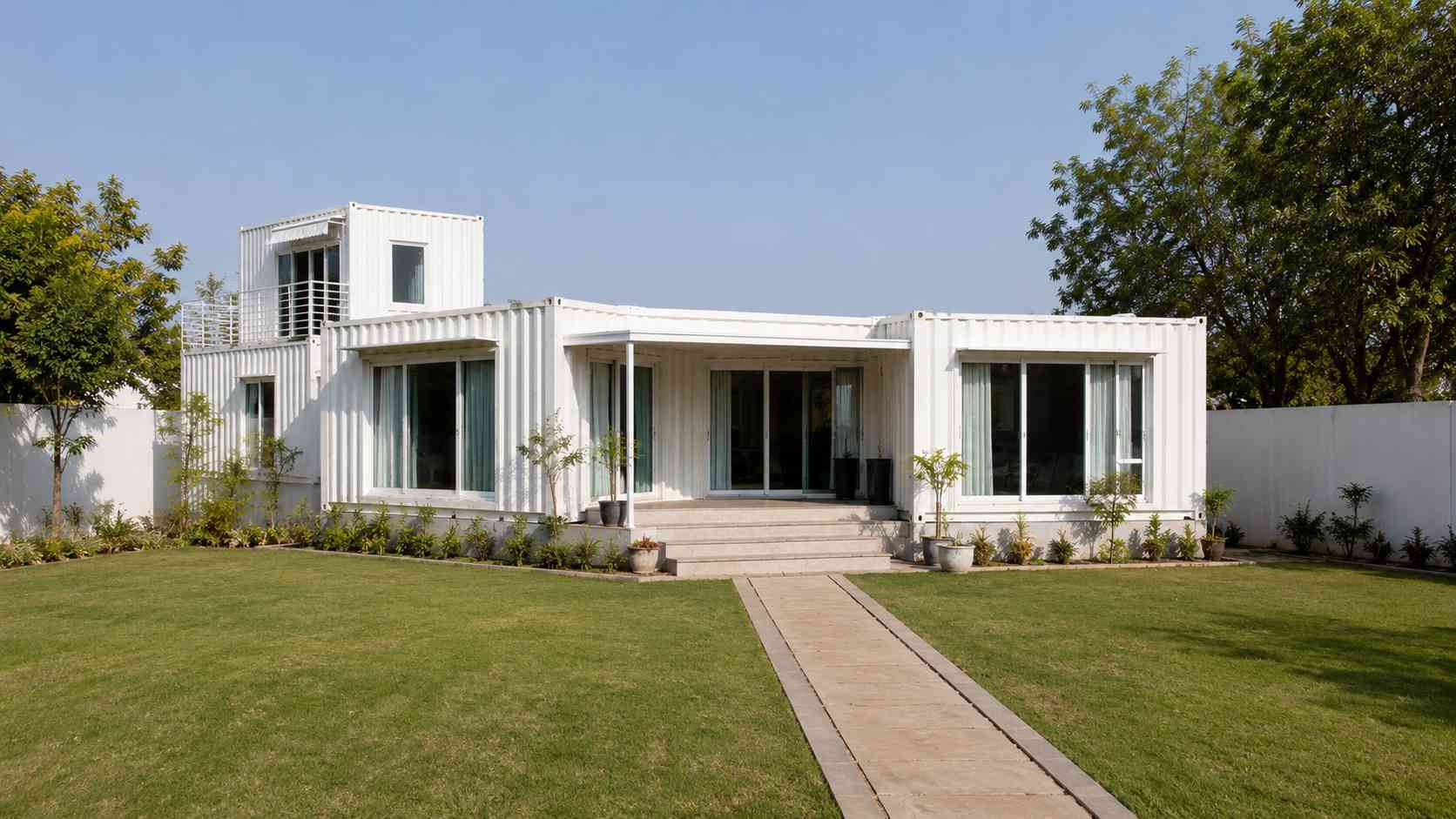 Finished white prebuilt container home standing complete on an Indian residential plot.