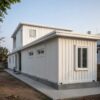 Side view of a white prebuilt container home showing joined container modules and length.