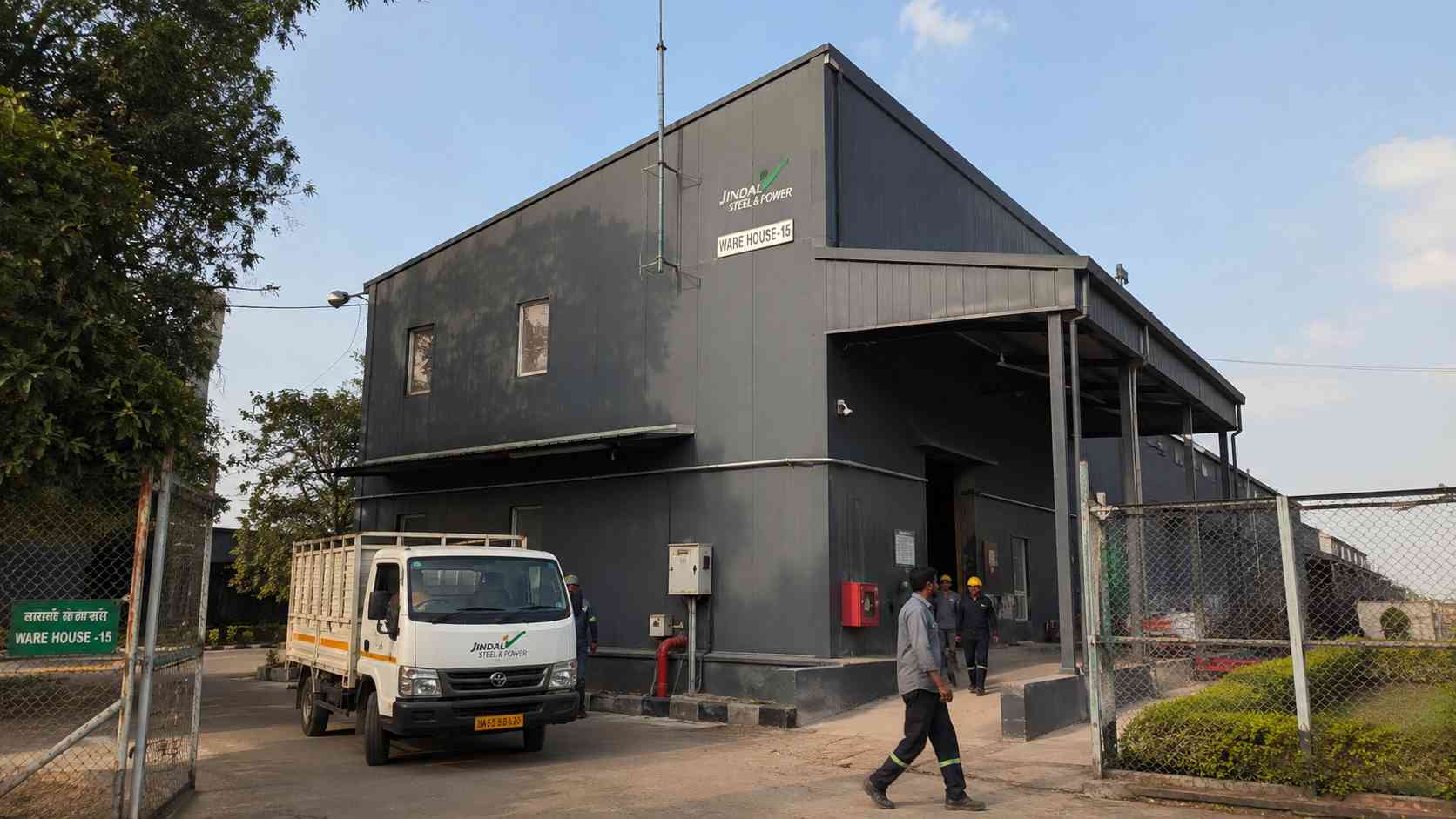 Charcoal prefab building in operational use on a small industrial compound with a goods vehicle at the entry.