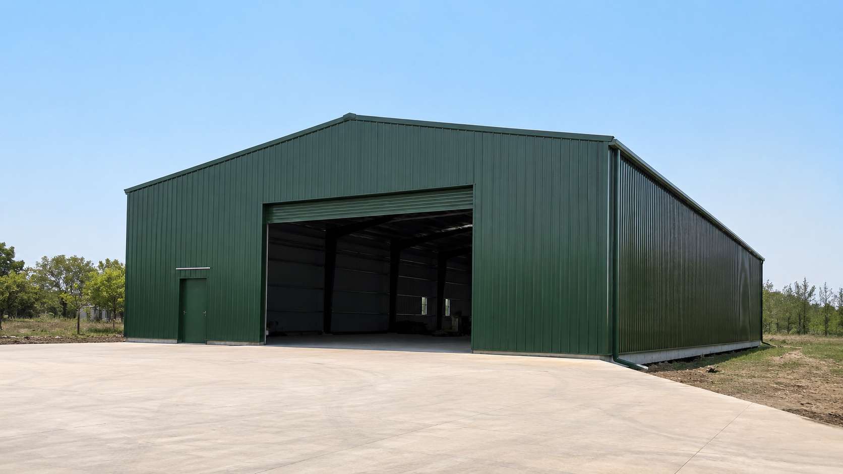  Green wide-span steel-frame prefab building with a column-free interior on an industrial estate.
