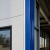 Close-up of a white PUF panel wall meeting blue steel trim on a prefab building corner.