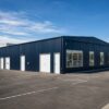 Navy metal-clad prefab commercial building elevation showing wall panels, windows and entry doors.