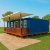 SAMAN prefab container home in marine blue with extended roof, wooden porch, red seating, and paved patio approach.