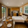 Interior of SAMAN prefab container home with dining table set for breakfast, fitted kitchen, double bed, and balcony slider door.