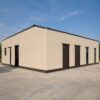 Side view of a black steel prefab industrial building with two large roller shutters.