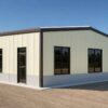 Sage green prefab industrial building front with office windows and a personnel entrance.