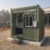 Sage Industrial green 10×10 ft prefab labor hutment with door open showing the interior dorm.