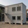 Side elevation of a Pearl Grey G+1 prefab labor hutment with external steel staircase.