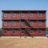 Front elevation of a burgundy red G+2 three-storey prefab labor shed with fifteen worker rooms by SAMAN Portable