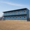 Side elevation of a twelve-room steel-blue G+1 prefab labor shed with continuous upper-floor walkway by SAMAN Portable