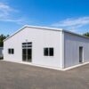 Front of a prefab manufacturing building with a wide roller-shutter entry for material movement.