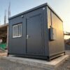 Slate Charcoal prefab mobile office entry door and concrete pad foundation seen from low front angle.