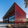 Crimson-red ribbed metal cladding and glazed frontage on a prefab modular commercial building.
