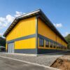 Completed yellow and grey prefab modular industrial building on an Indian project site.