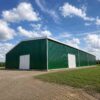 Long green prefab modular warehouse building with white gable end and personnel doors.
