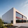 Off-white two-storey prefab modular commercial building with dark glazing and paved forecourt.
