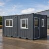 Steel grey prefab office building in use at a worksite with staff entering