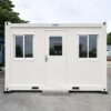 White prefab site office shown straight-on from the front with door and two windows.