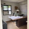 Site engineer working at a desk inside a prefab site office with project drawings.