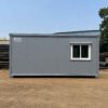 Steel grey prefab site office seen from the side on a project site.