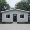 Pearl grey prefab steel house front elevation with a central door and two windows.