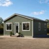Sage green prefab steel house with windows and a residential entry door on a level plinth.
