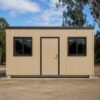 Front view of a sandstone-beige prefabricated bunkhouse with a centred door and two windows.