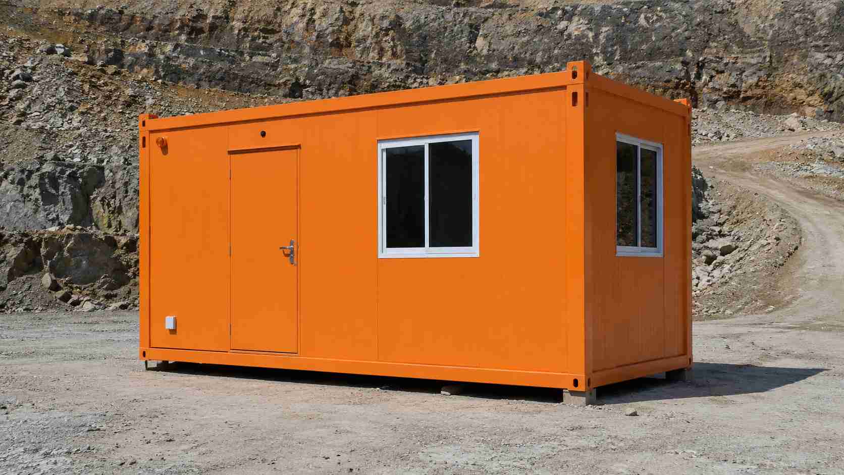 A safety-orange prefabricated bunkhouse on a pad at a mining lease with rock benches behind.