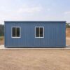 Side view of a steel-blue prefabricated bunkhouse showing the long panel wall and roof line.