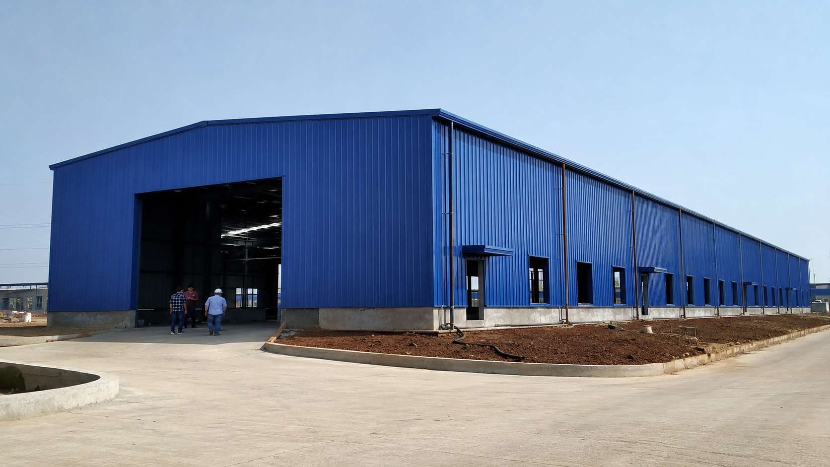 Royal-cobalt prefabricated steel building nearing completion on an Indian industrial plot.