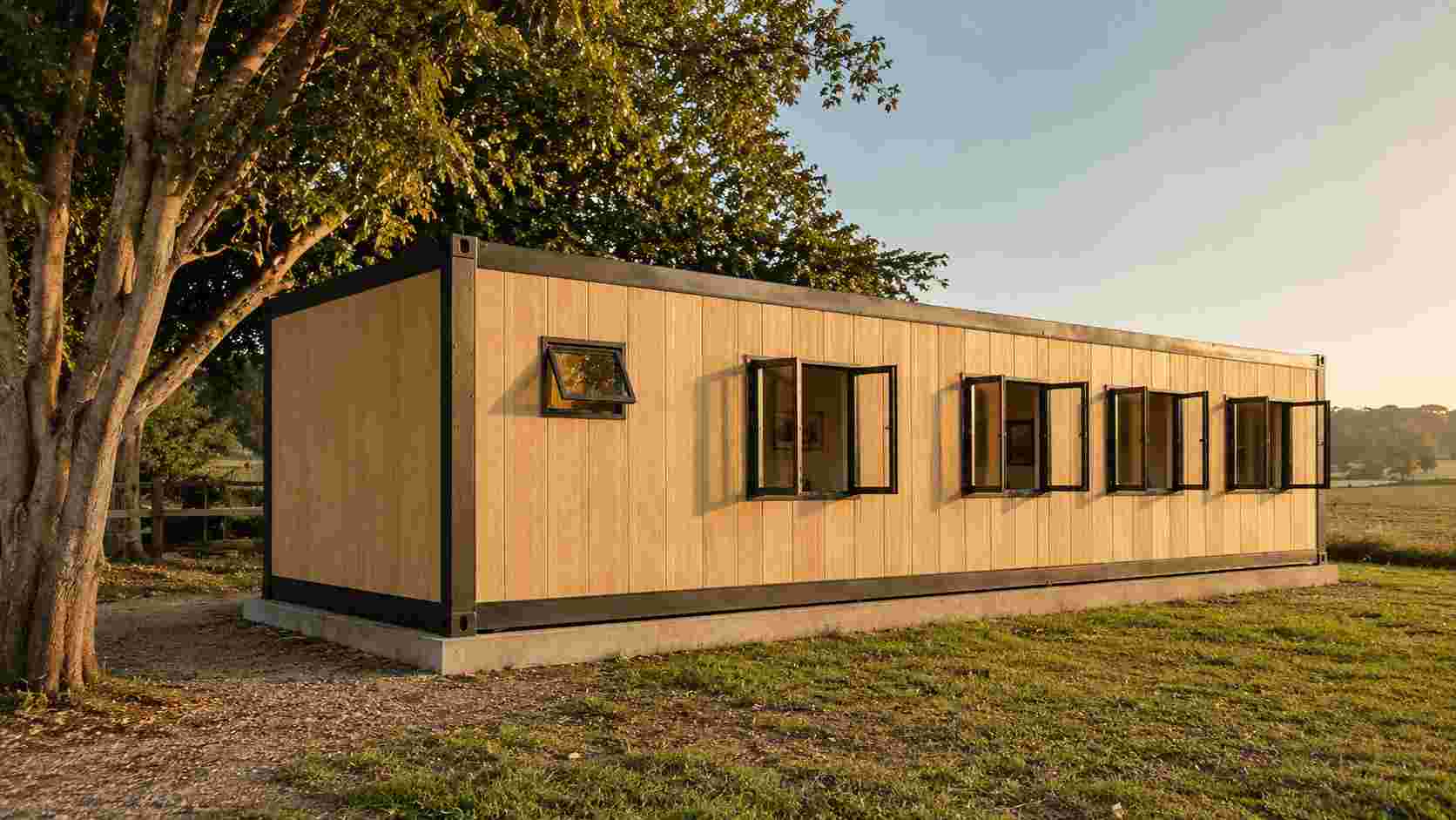 Prefabricated container house with sandstone beige wood-effect cladding upgrade in a farm setting