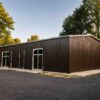 Brown prefabricated steel building installed on a paved commercial site with framed windows and doors.