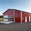 Red prefabricated steel building, 90 by 36 ft, with white roller and glass doors at dusk.