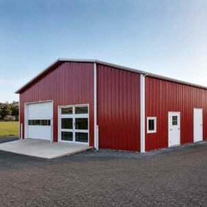 Red prefabricated steel building, 90 by 36 ft, with white roller and glass doors at dusk.